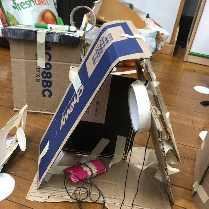 An incline plane is created with cardboard with wires that are also intertwined. 