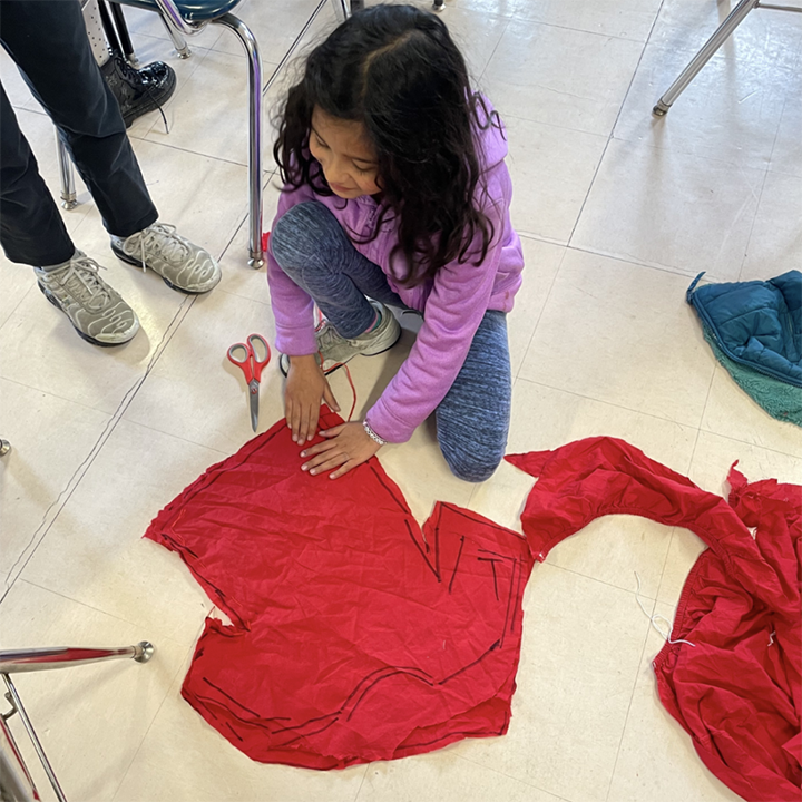 A red T Shirt is getting cut to become part of a new invention.