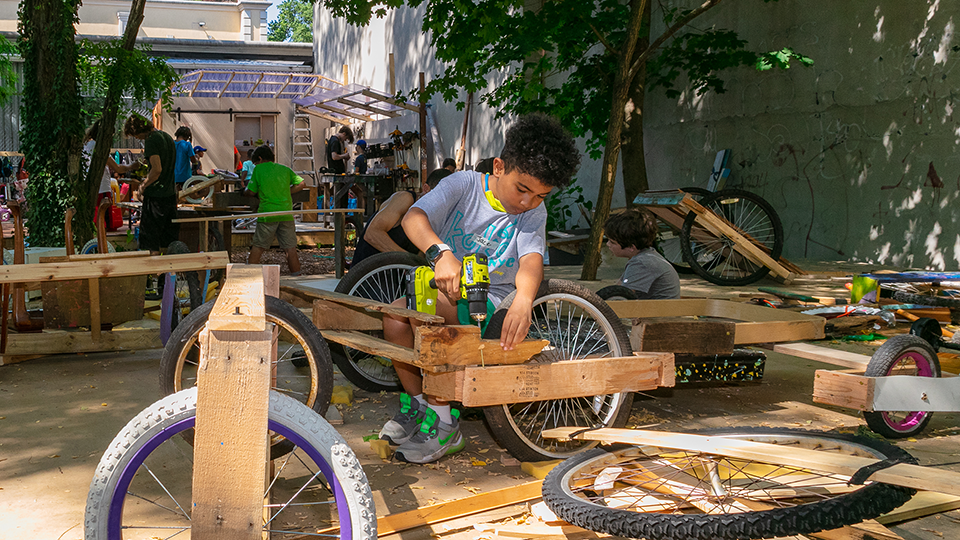 A camper drills wood to complete the frame for their SoapBox car.