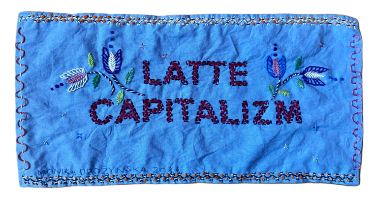 Embroidered blue image with Latte Capitlizm in black stitches on blue. 